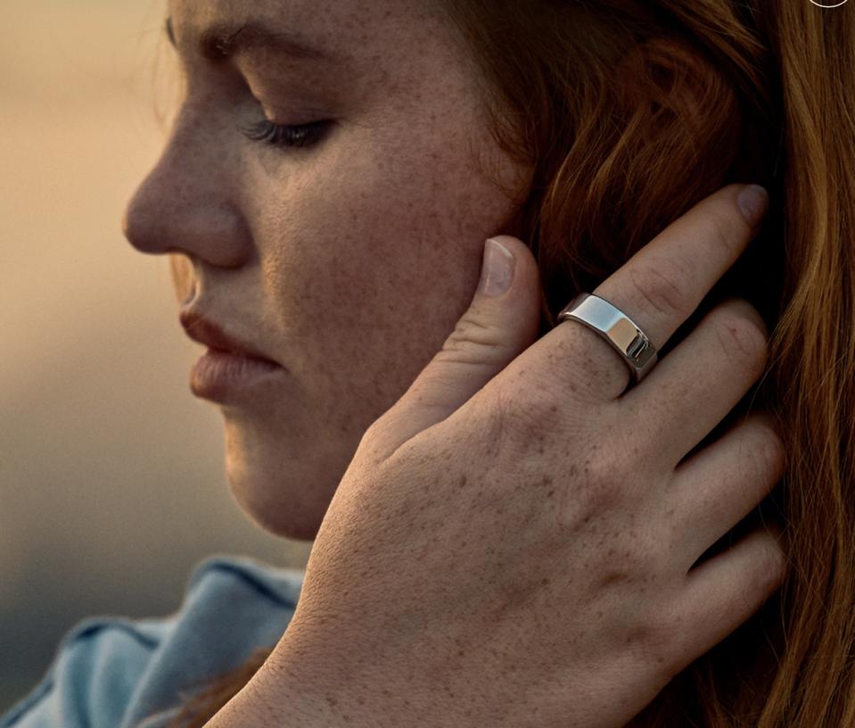 Close-up of woman shown in profile with her hand next to her face wearing the Oura ring.