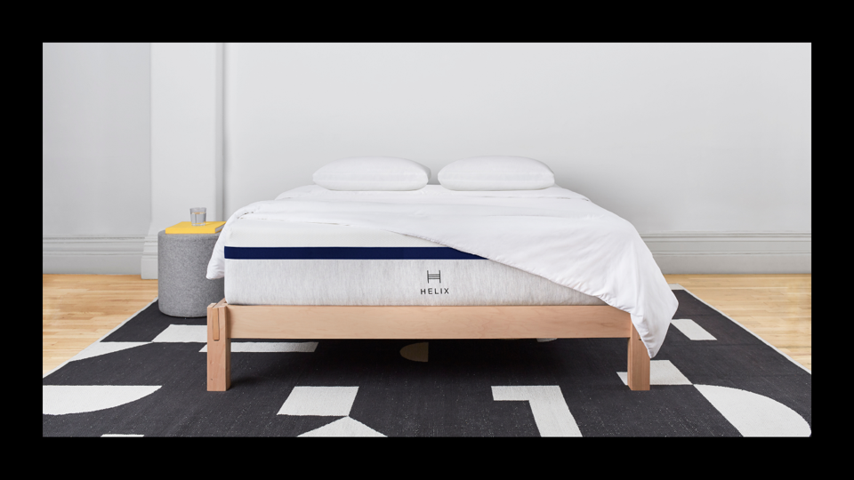 The Helix Midnight Mattress with a blanket and pillows on top. 