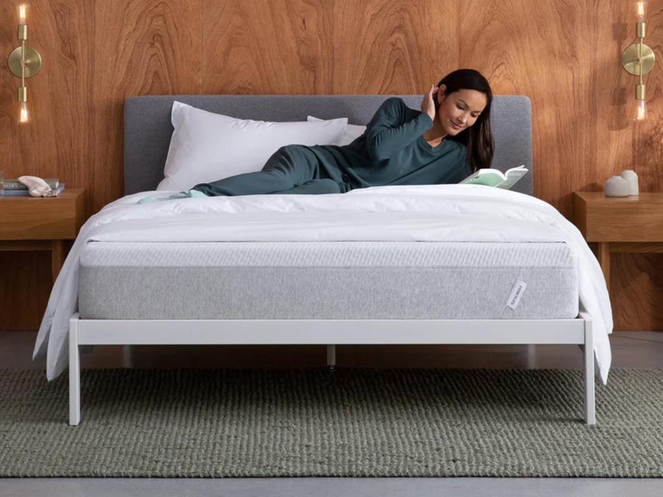 A woman reading while lying on the Essential T&N Original Mattress.