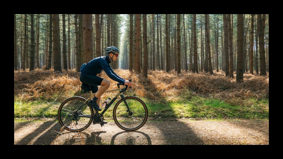 A man riding a gravel bike in the woods on a dirt path