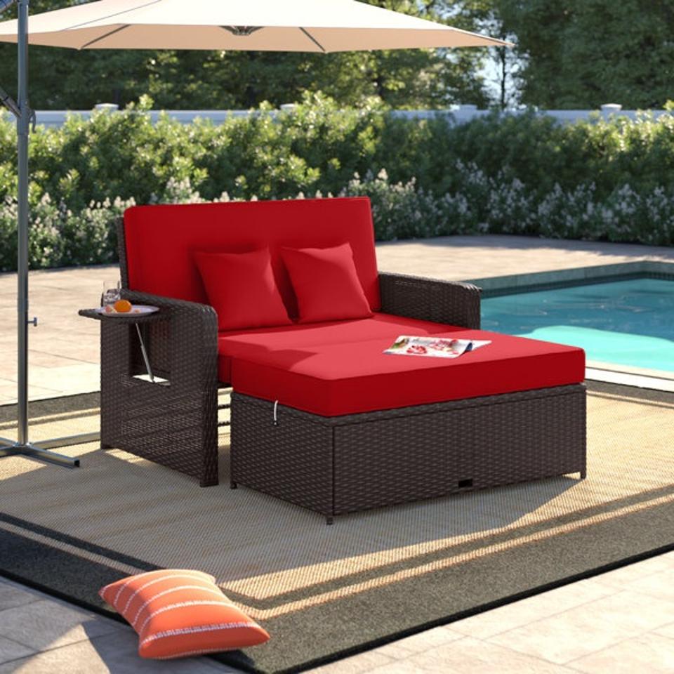 Lifestyle image of Wade Logan Armonee Outdoor Loveseat with red cushions by a pool