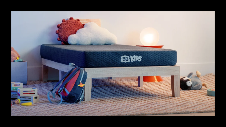 BB Kids Mattress on a platform bed, with toys and a backpack on the floor next it it