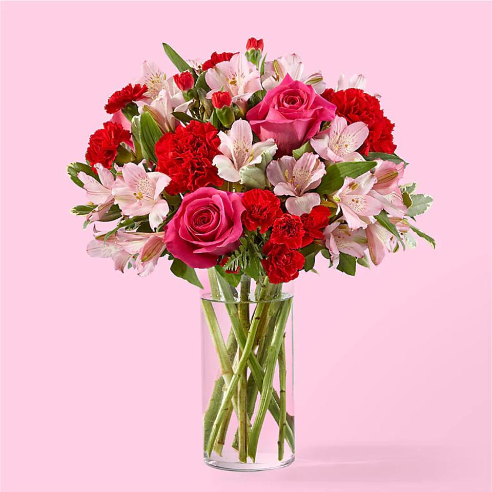 jewel-toned roses alstroemeria carnations in water clear glass jar pink background