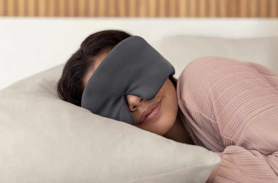 A woman wearing a sleep mask lying on her pillow. 