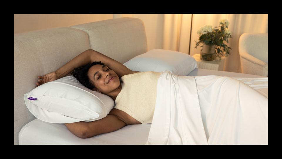 A woman lying on the Purple Harmony Pillow in bed.