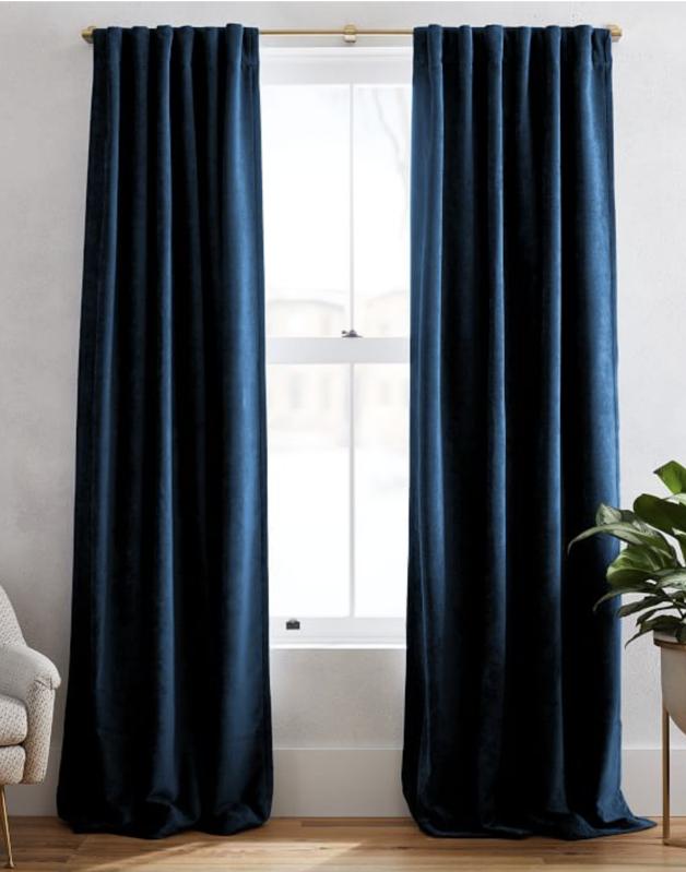 West Elm Worn Velvet Curtain in dark blue framing bright window.