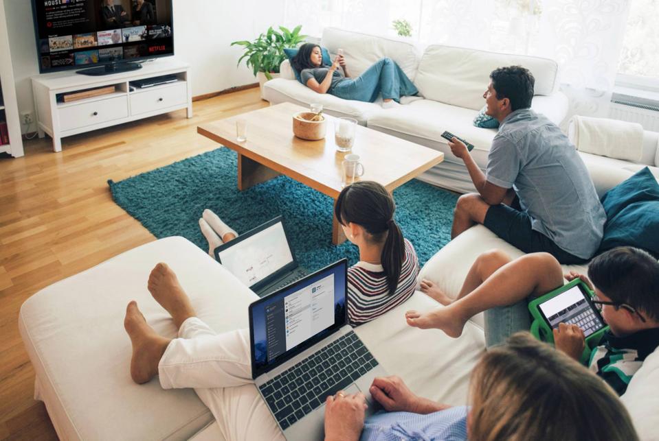 1Password being used on multiple devices by a family in a living room setting.