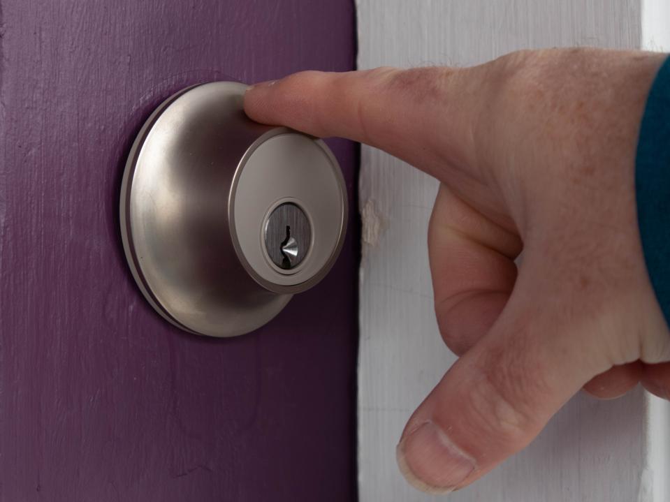 A hand touching the fingerprint sensor Level Lock Plus Connect on a purple door