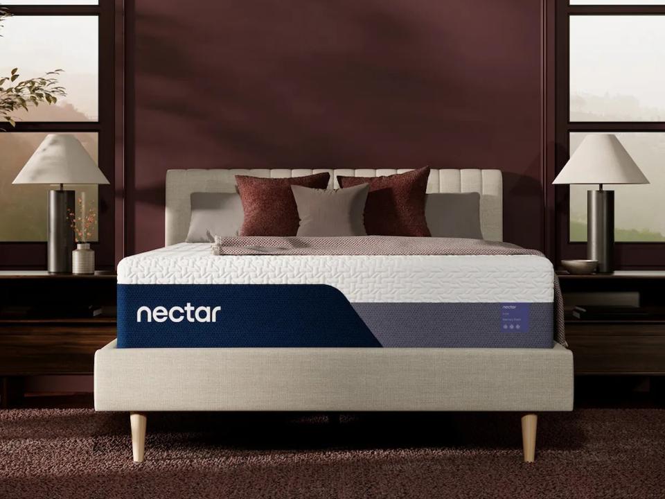 The Nectar Luxe on a bed frame in front of a red wall.