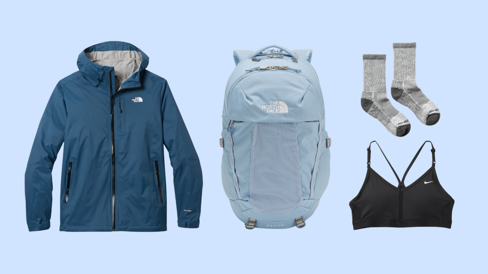 A rainjacket, backpack, pair of socks and sports bra against a light-blue blackground. 