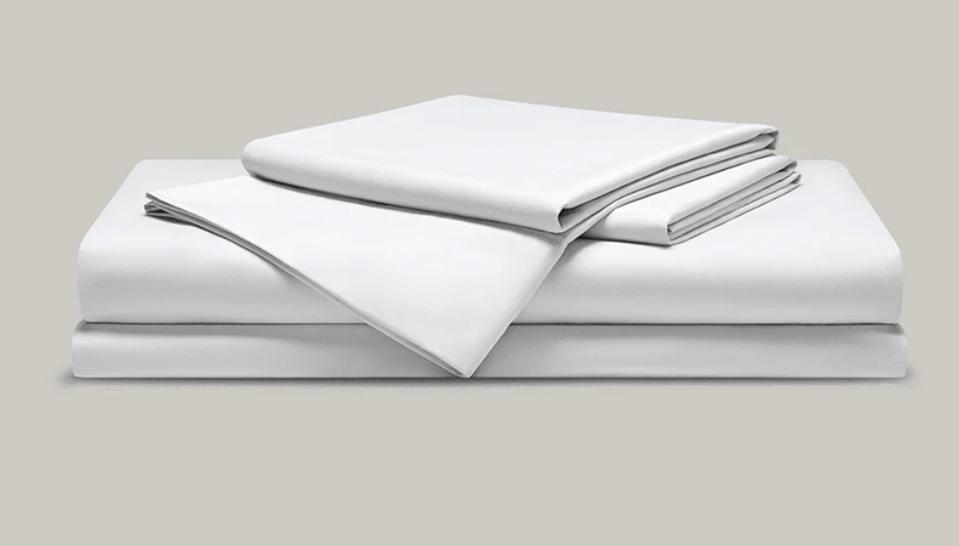 A stack of Coop Sleep Goods white sheets on a putty colored background