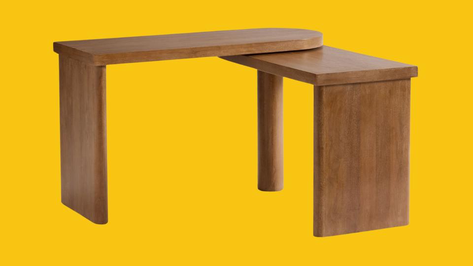 The Pottery Barn Cayman L-Shape Rotating Desk against a yellow background.