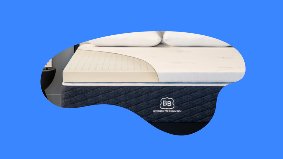 A Bed with a mattress pad on top and two pillows.