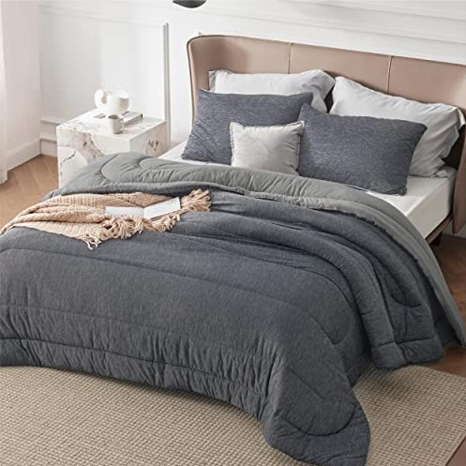 The Bedsure Queen Comforter Set in dark gray on a mattress in a room.