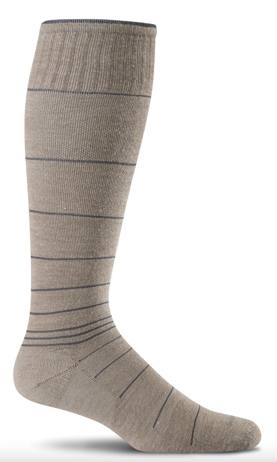 A tan knee-high compression sock from Sockwell with grey stripes on a white background