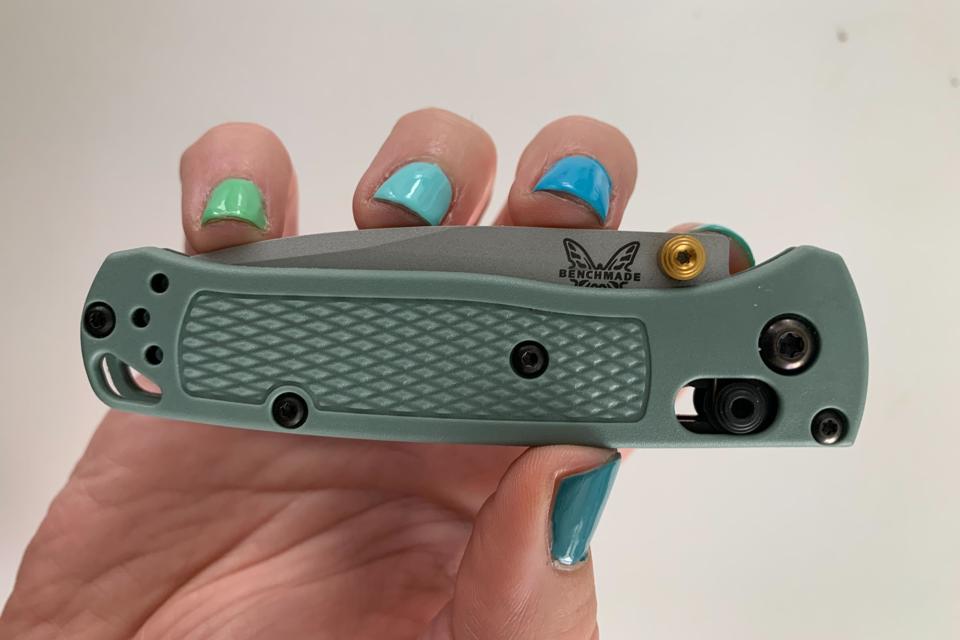 Benchmade Mini Bugout 2 in grey with a hand holding the pocket knife with painted nails