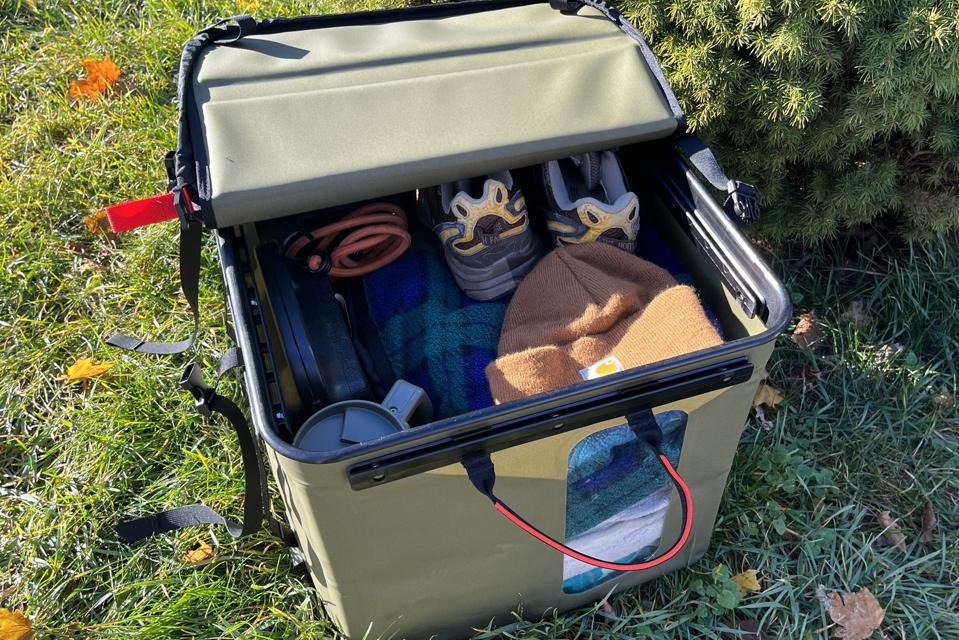 The Rux 70L Storage System filled with a hat, shoes, a bungee cord and a blanket