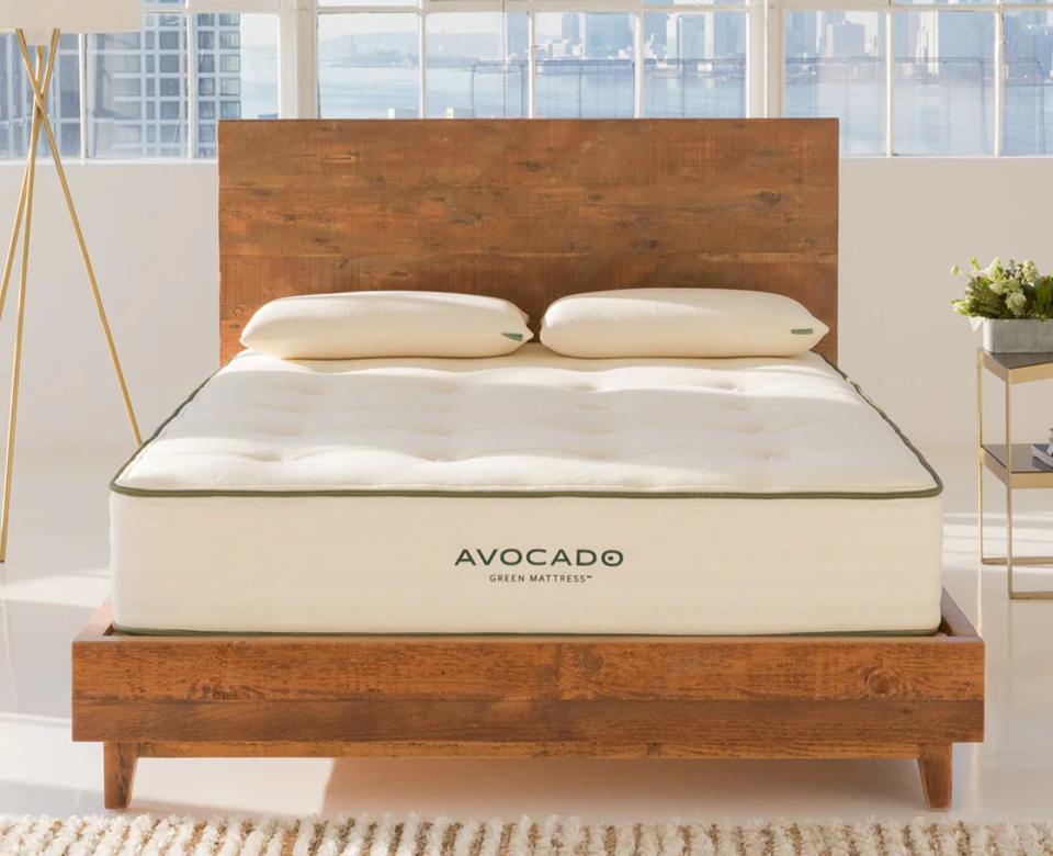 Lifestyle shot of the Avocado Green Mattress in a window-lined apartment with skyline view