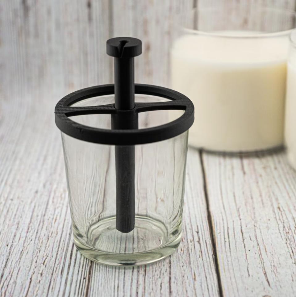 A wick-centering tool in a jar on a wooden background.