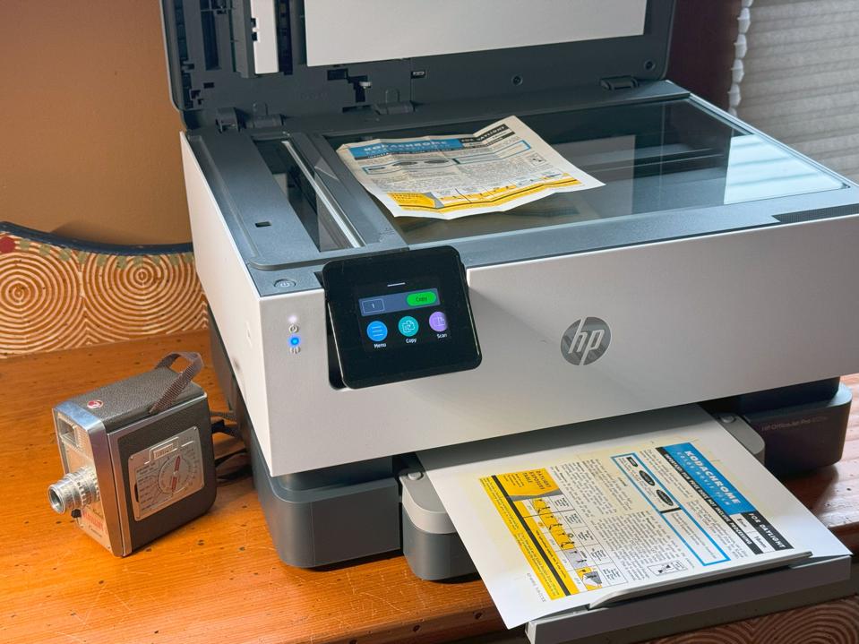 HP OfficeJet 9125e on a tabletop. There's a sheet in the scanner tray and the paper tray.