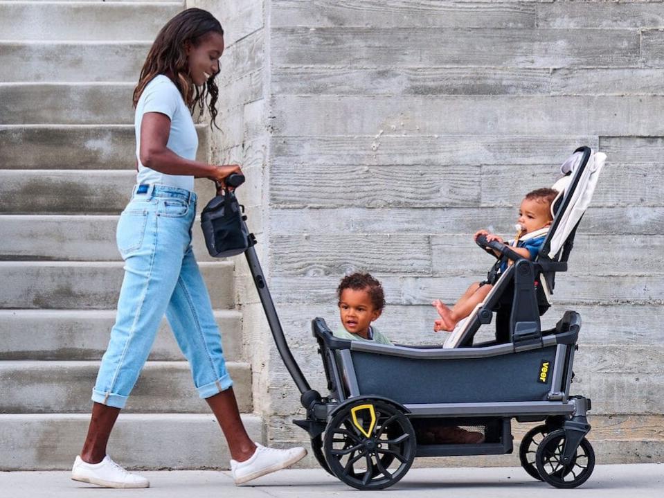 mom pushing veer Cruiser City xl wagon w/ 2 kids outside in daytime