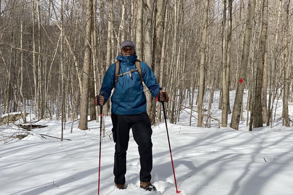 A man holding the Black Diamond Pursuit FLZ trekking poles in a snowy wooded area