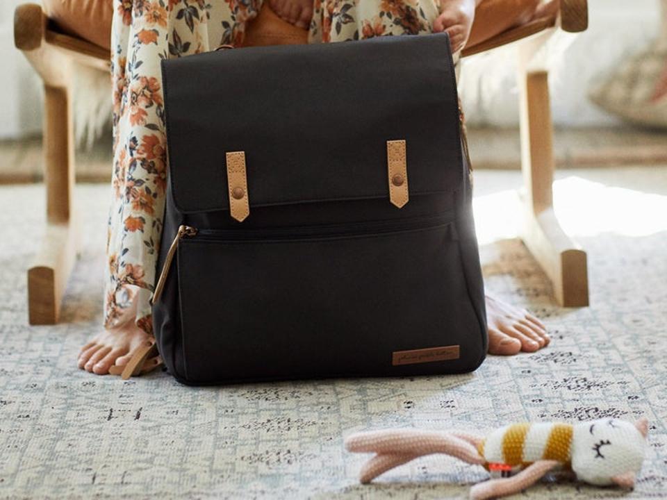 Black Petunia Pickle Bottom Meta Backpack sitting at the feet of a women and a child.