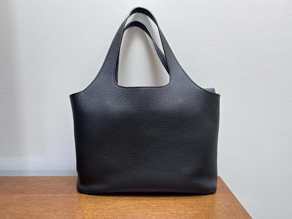 Cuyana System Tote in black sitting on a wooden table against a white backdrop