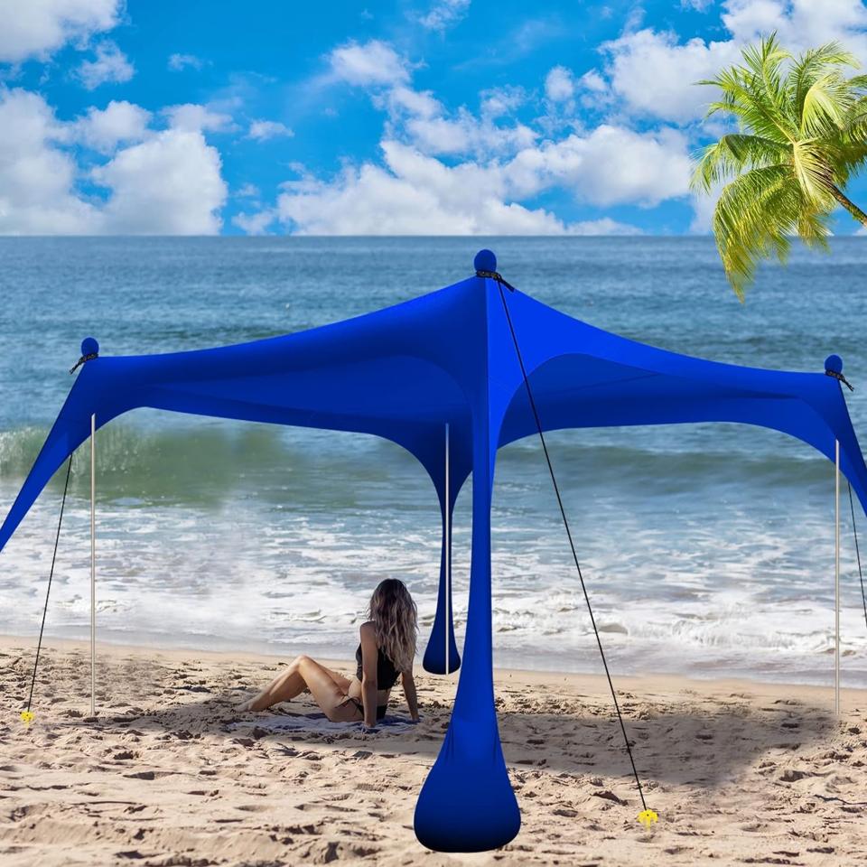 Buheco Beach Tent Pop Up in blue on the beach with a woman sitting underneath