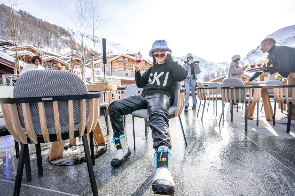 A woman smiling while wearing ski attire on a patio