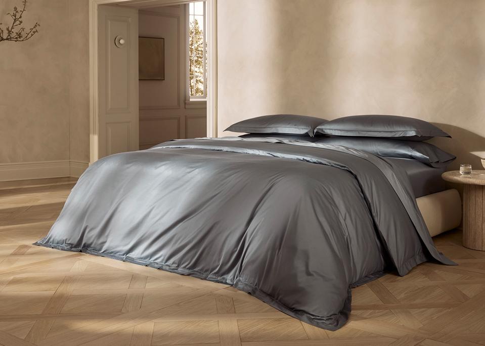 the Boll & Branch Summit Supima Duvet Set in Bluestone on a bed in a brown room