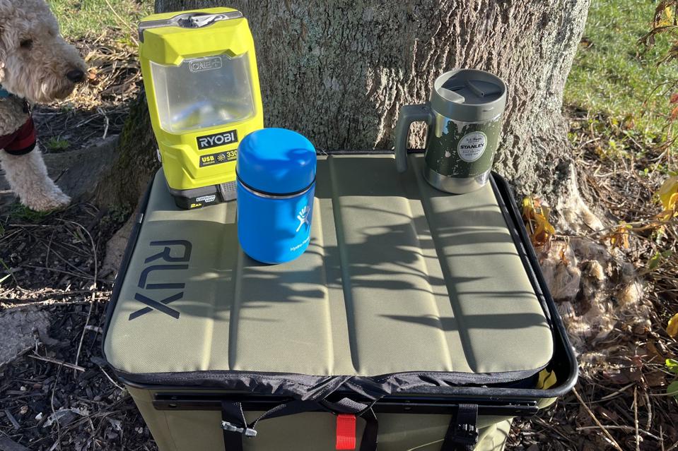 The Rux 70L Storage System with a flashlight and water bottles resting on the lid