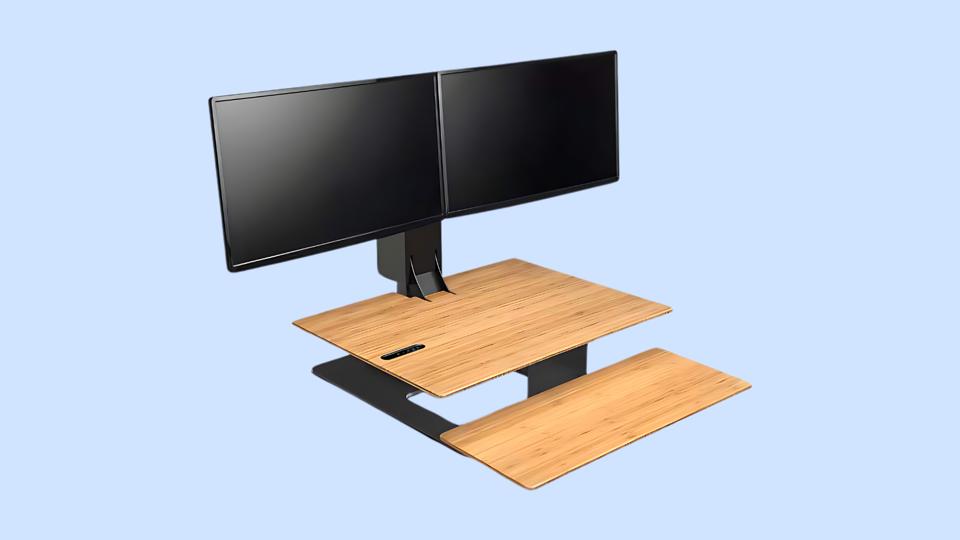 The E7 Electric Standing Desk Converter on a light blue background