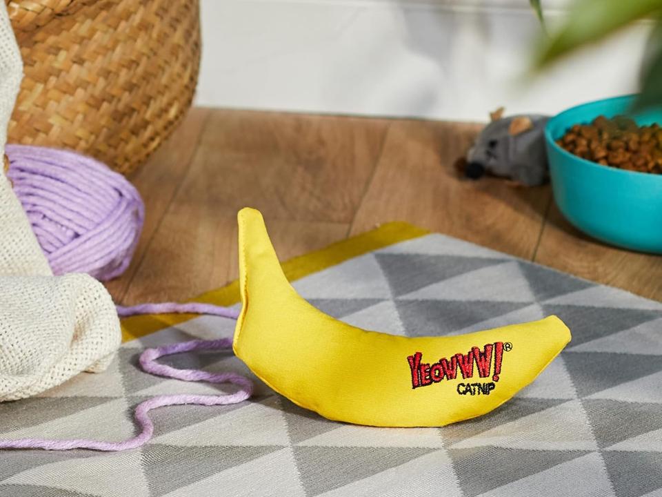 Yeowww! Catnip Banana on the floor next to a bowl of cat food