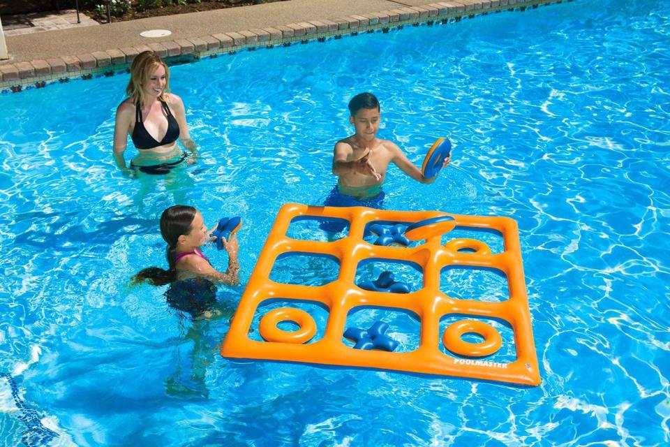 A mom and two kids playing the Poolmaster Tic Tac Toe Game in a pool on a sunny day