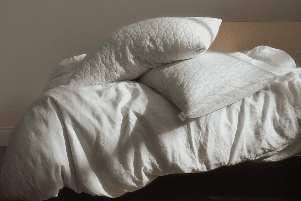 Two Coop Sleep Goods Original Adjustable Pillows on a bed.