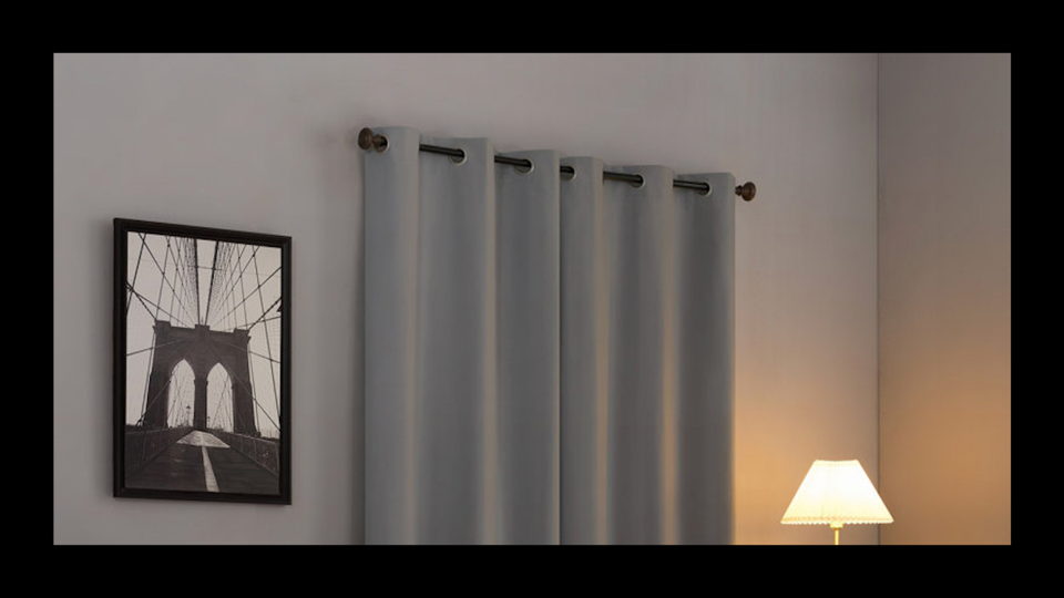 A dimly lit room with a pair of blackout curtains hanging from a rod over a window