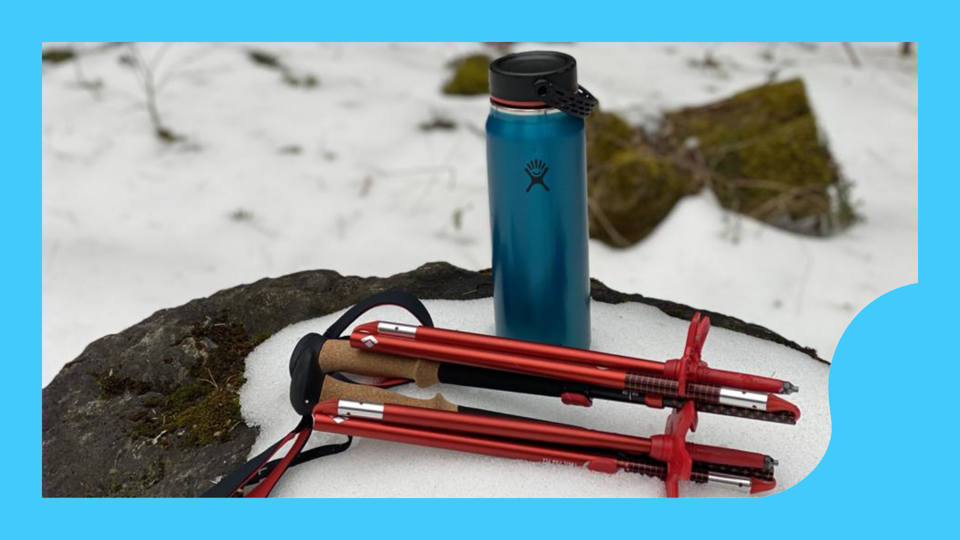 The Black Diamond Pursuit FLZ Trekking Poles folded up in the snow next to a blue bottle