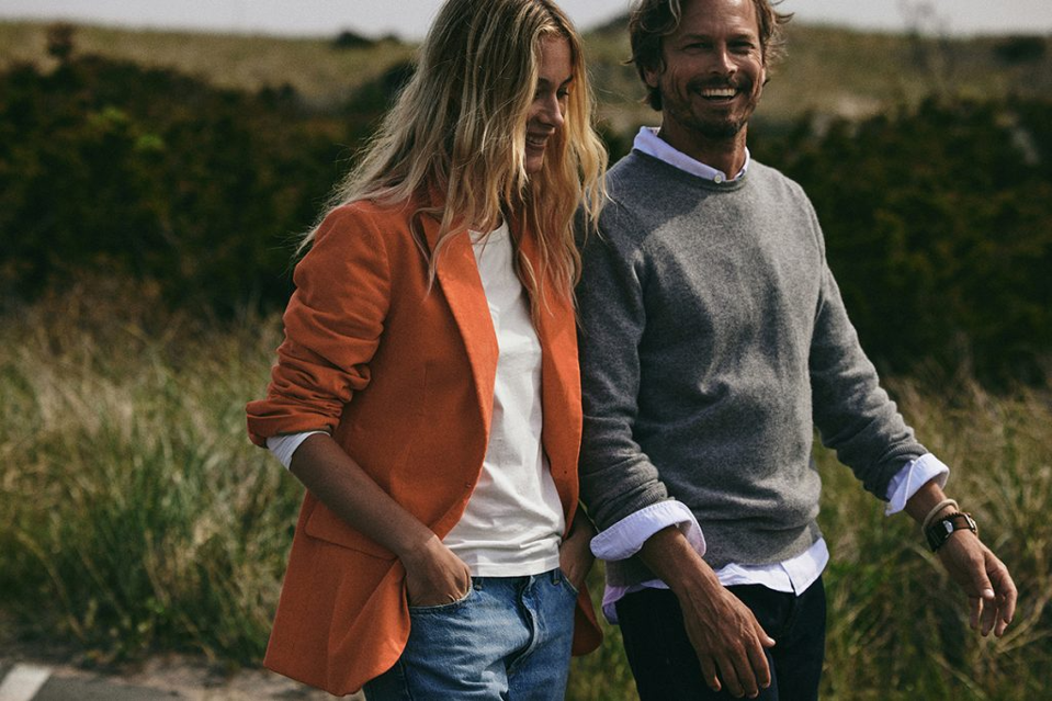 A man and woman walking on the beach next to each other smiling