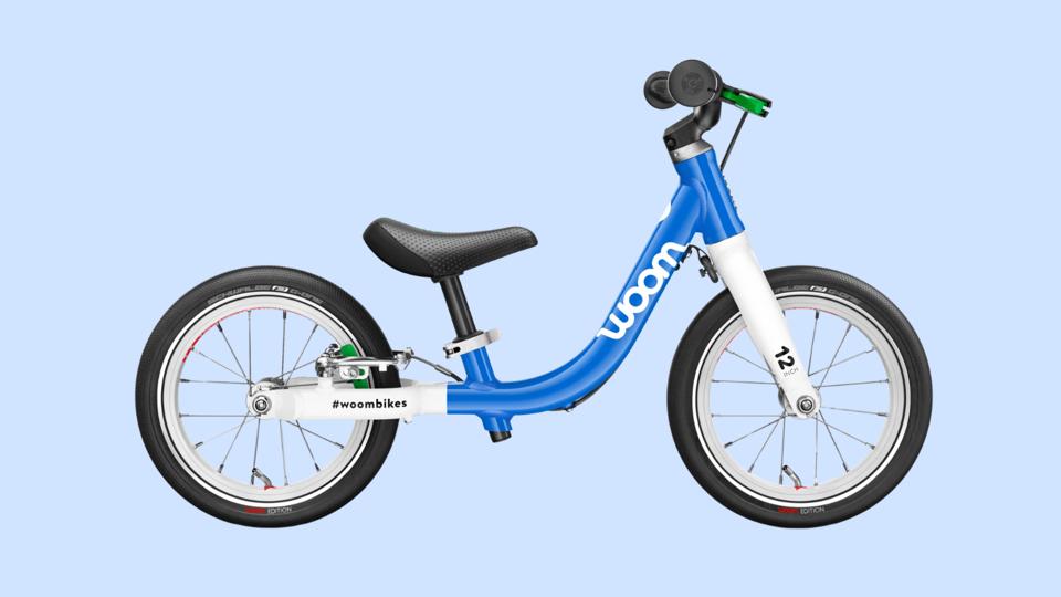 blue Woom balance bike on a light blue background