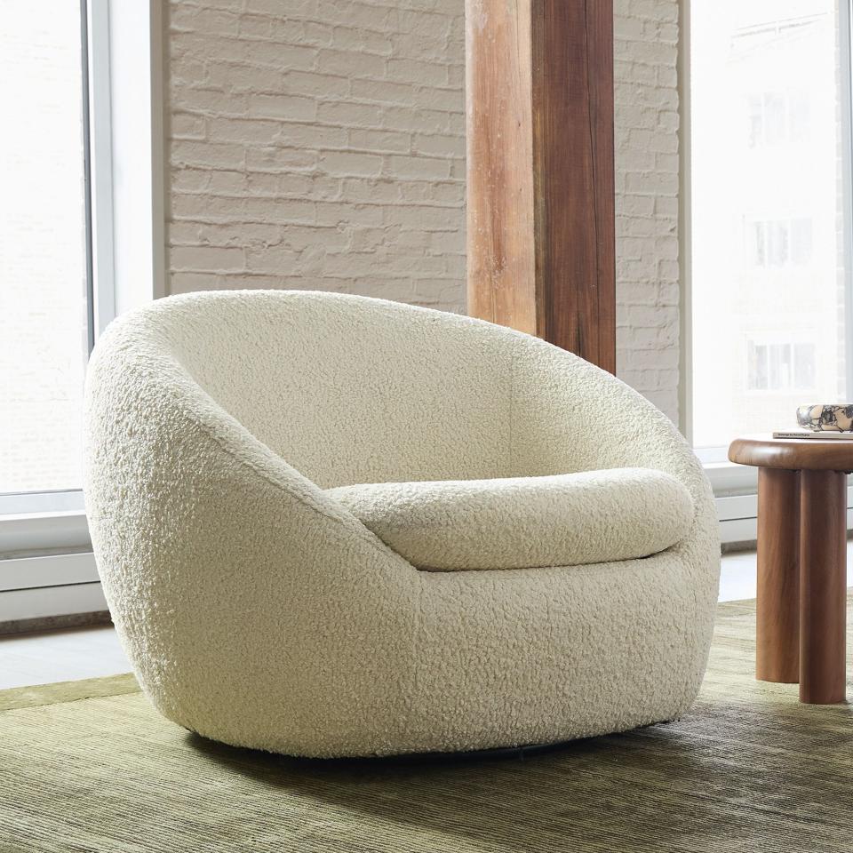 West Elm Cozy Swivel Chair next to a wooden table.