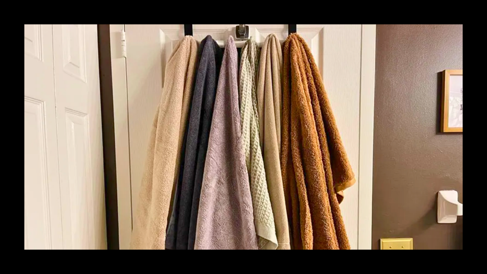 original photo of 6 bath towels of multiple colors and textures hanging on bathroom door