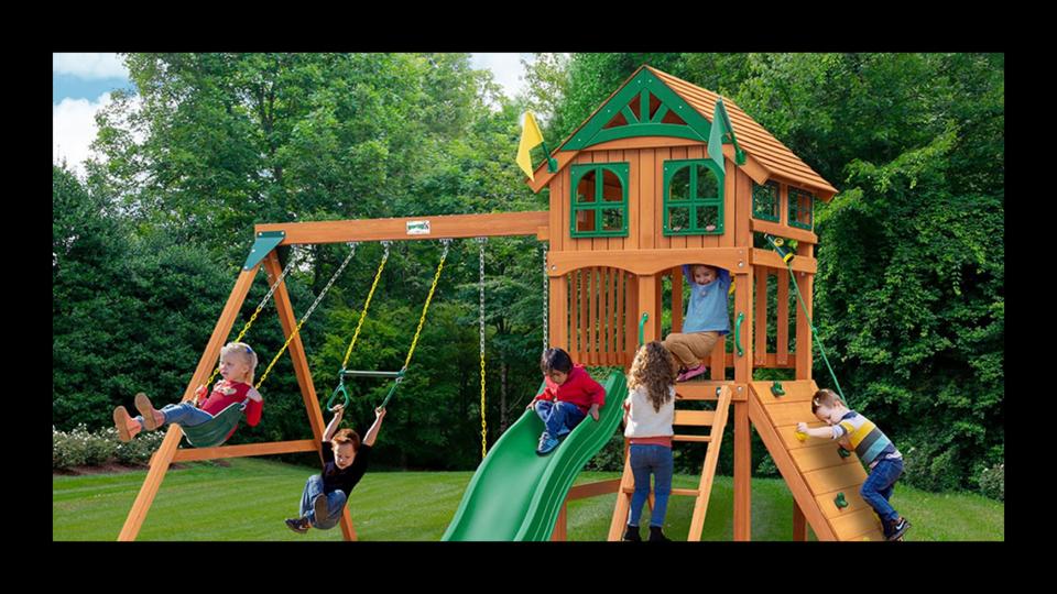 6 kids play on the Gorilla Playsets DYI Outing III in a backyard with grass and trees