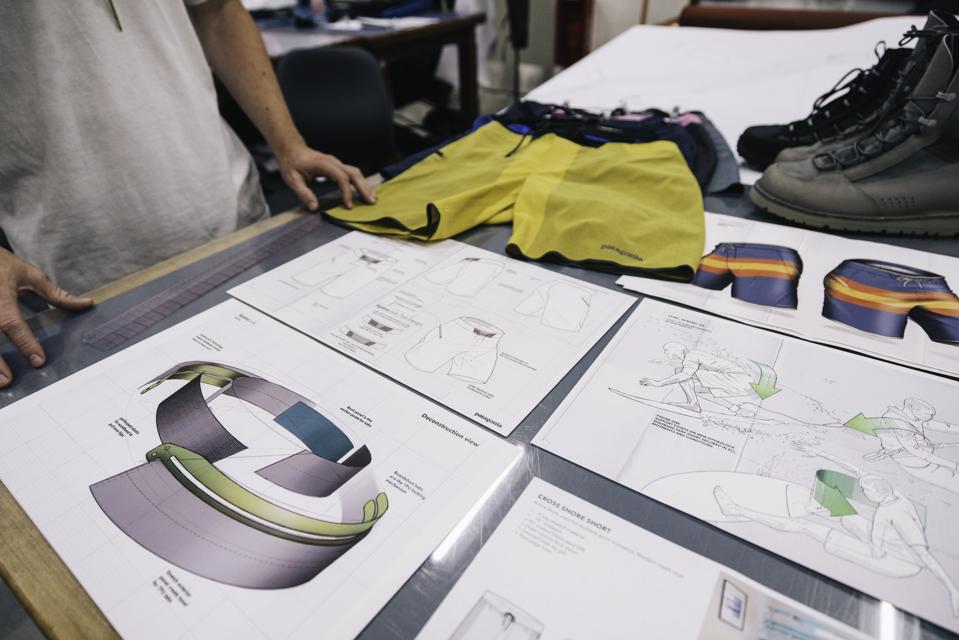 A man standing next to a work station with design visuals for a pair of shorts