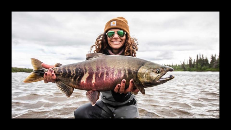 A woman holding a chum salmon on the water on Alaska