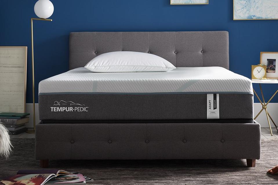 The Tempur-Adapt Mattress on an upholstered gray bed frame in a blue bedroom. 