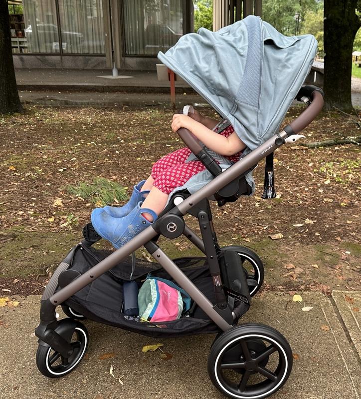 A 2-year-old child in the Cybex e-Gazelle e-stroller on a sidewalk