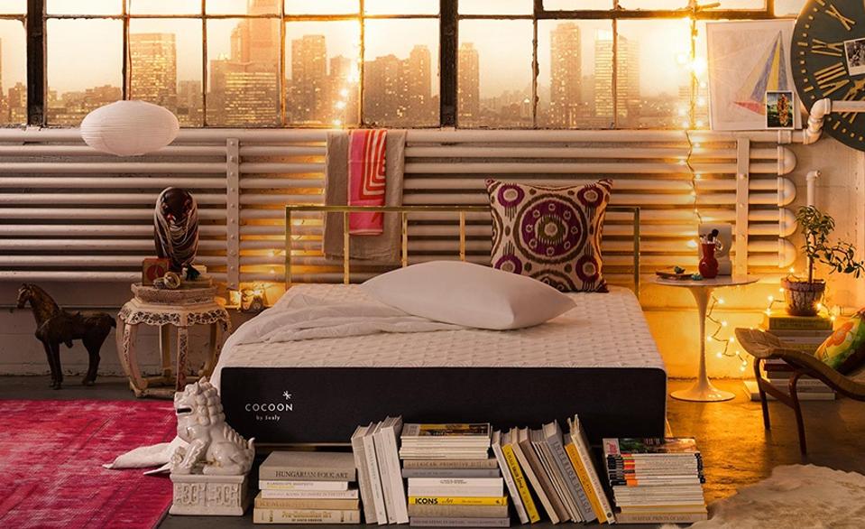 A Cocoon Sealy Chill Mattress in a city apartment with books on the floor near the foot. 