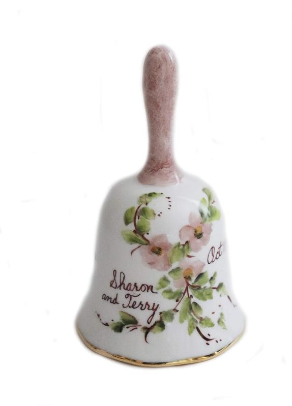 Personalized Porcelain Wedding Bells decorated with pink flowers green leaves 'sharon and terry' on left date on right against white background