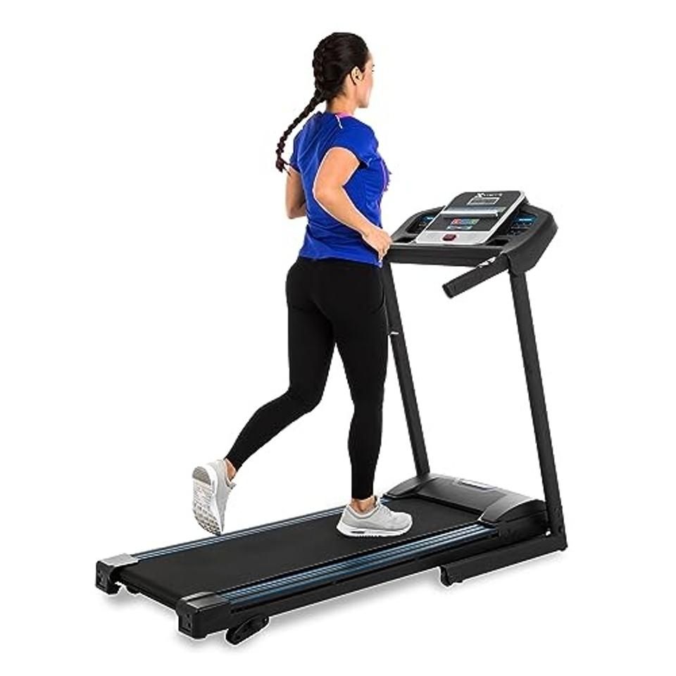 A woman in a blue shirt and braided hair running on the XTERRA Fitness TR150 Folding Treadmill